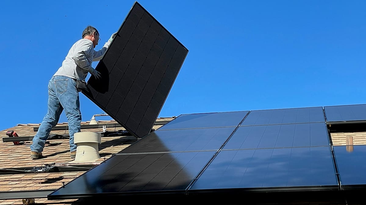 European residential home with rooftop solar panels and a modern heat pump unit installed.
