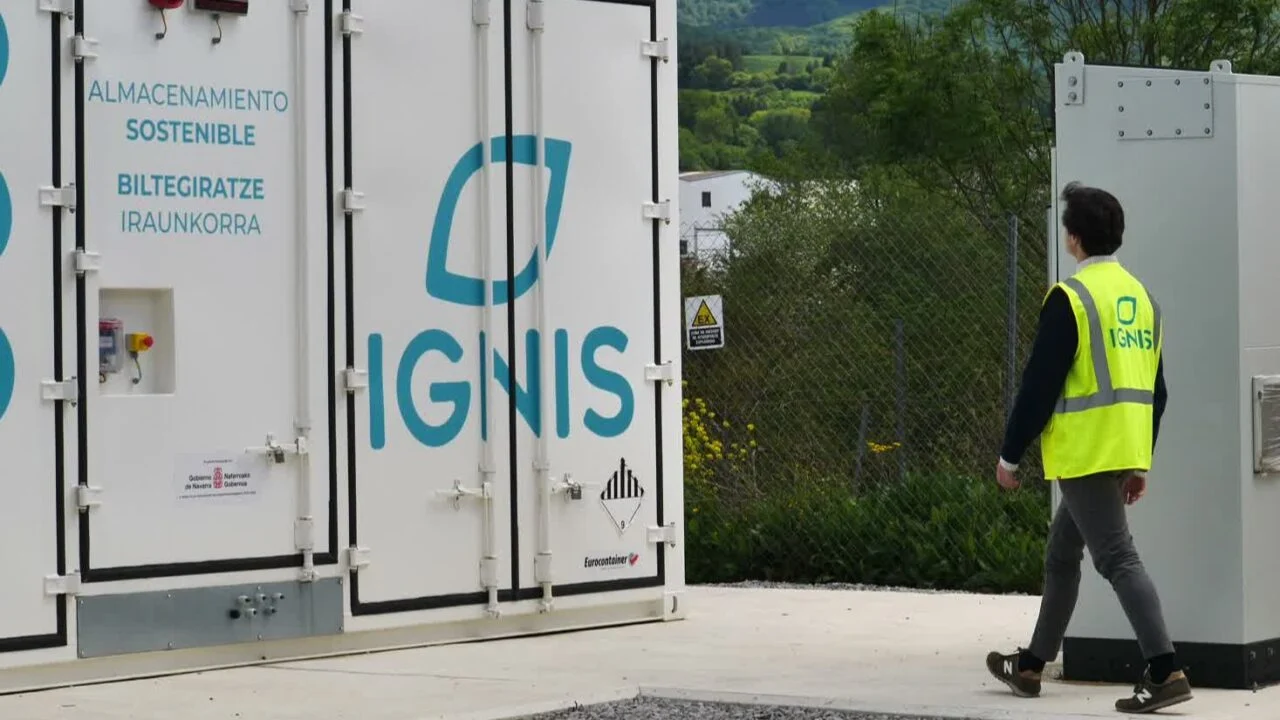 Large scale battery energy storage system containers in a sunny Spanish landscape near solar panels.