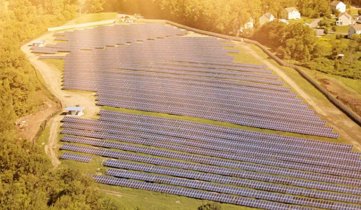 Aerial view of a massive utility-scale solar farm with integrated battery storage units in a desert landscape.