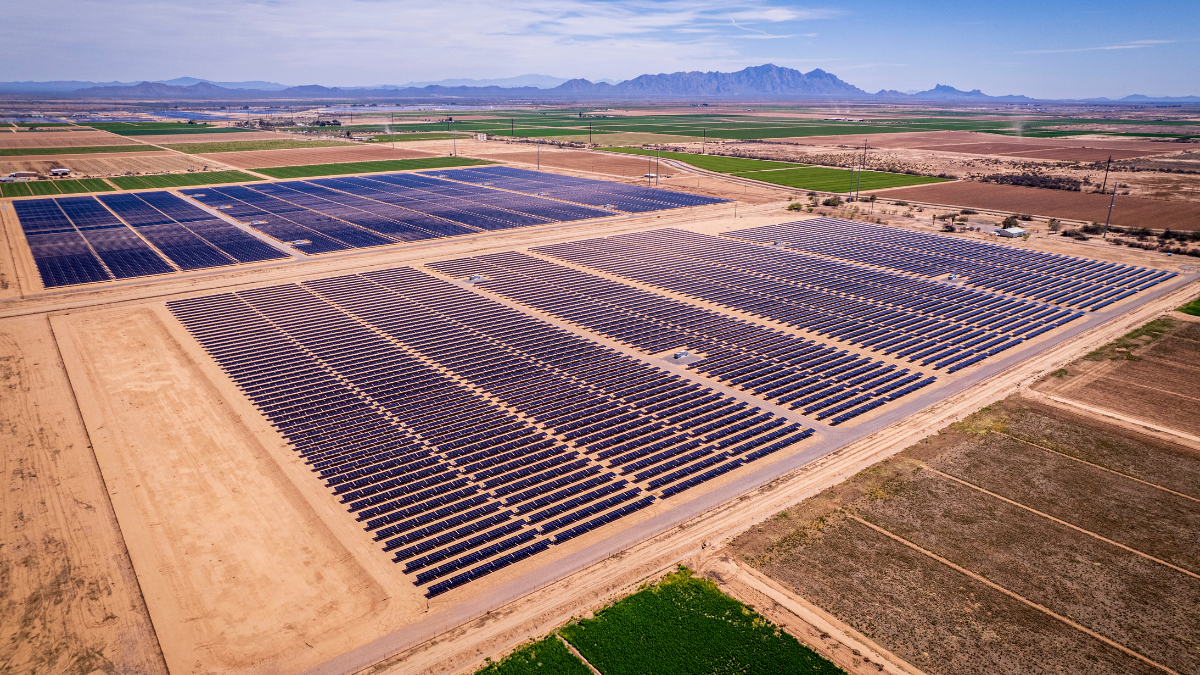 Aerial view of a massive solar farm and battery energy storage containers in a desert landscape