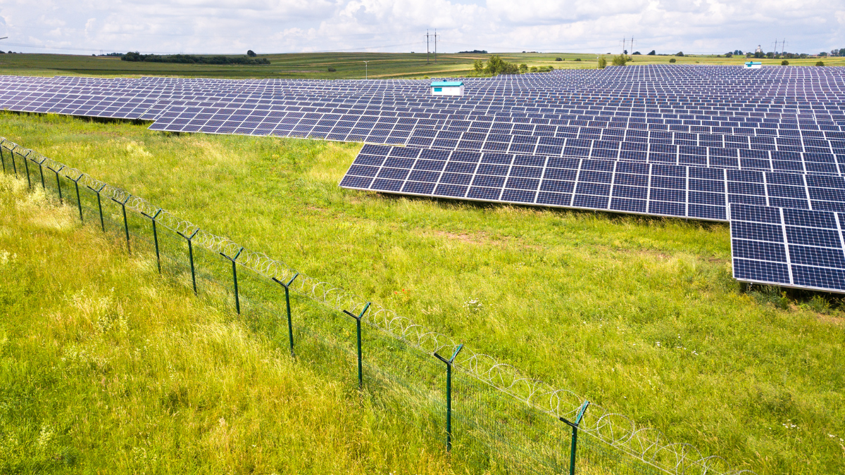 Aerial view of a massive utility-scale solar farm with thousands of blue PV panels under a clear sky.