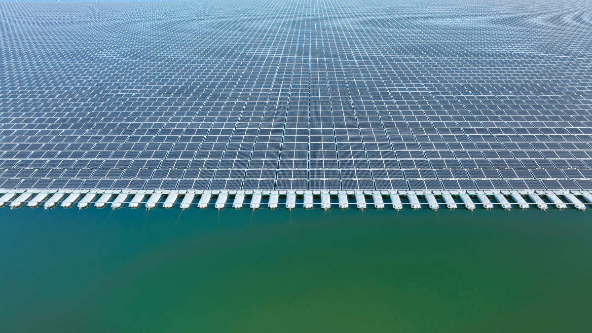 Floating solar panels on a calm industrial reservoir with blue sky reflection