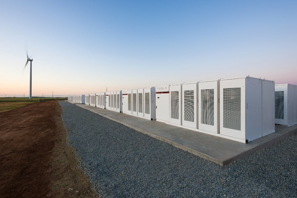 Large scale battery storage containers in a field under a bright sun