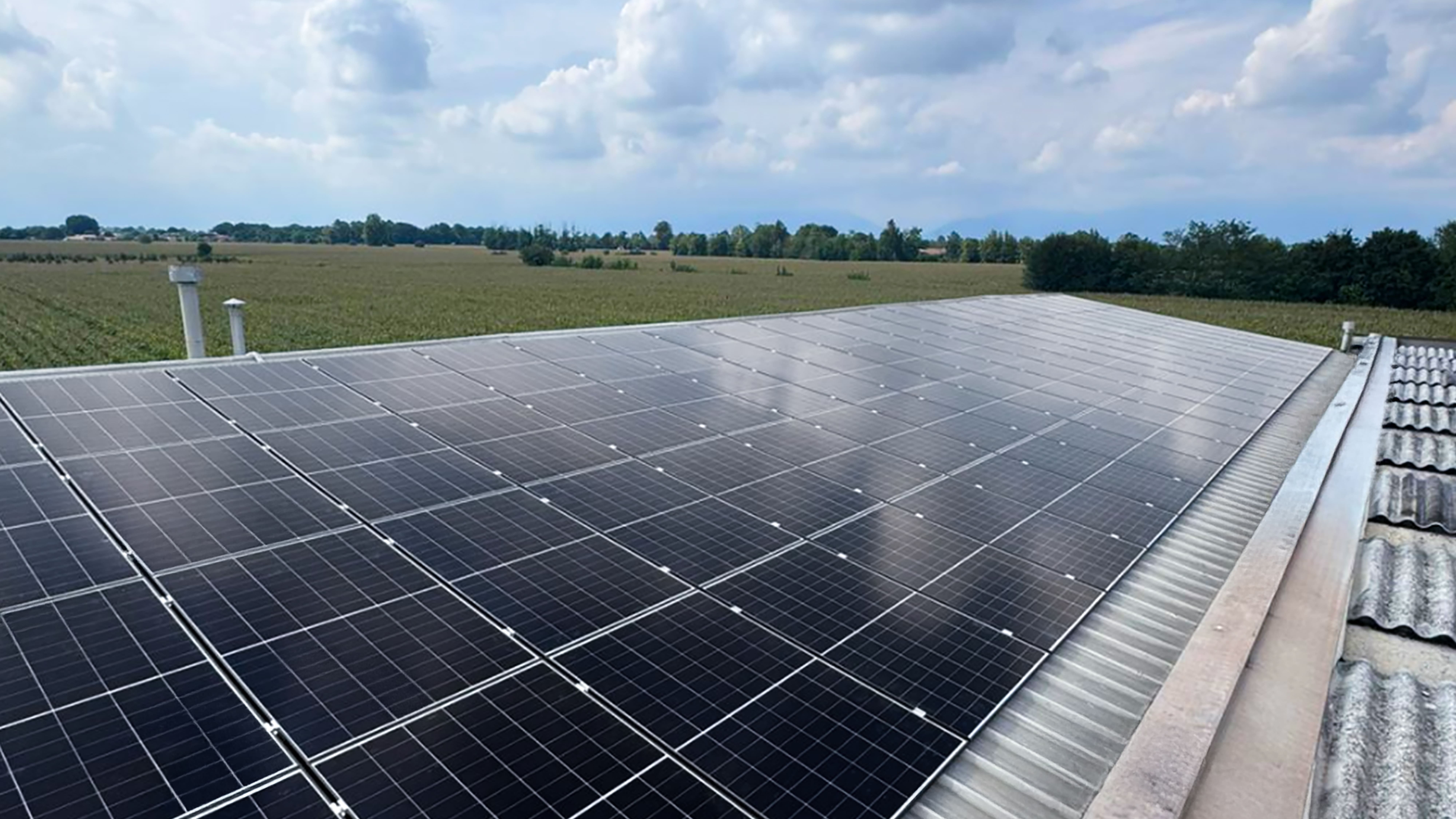 A row of high-efficiency Aiko N-type solar panels installed on a corrugated metal industrial roof.