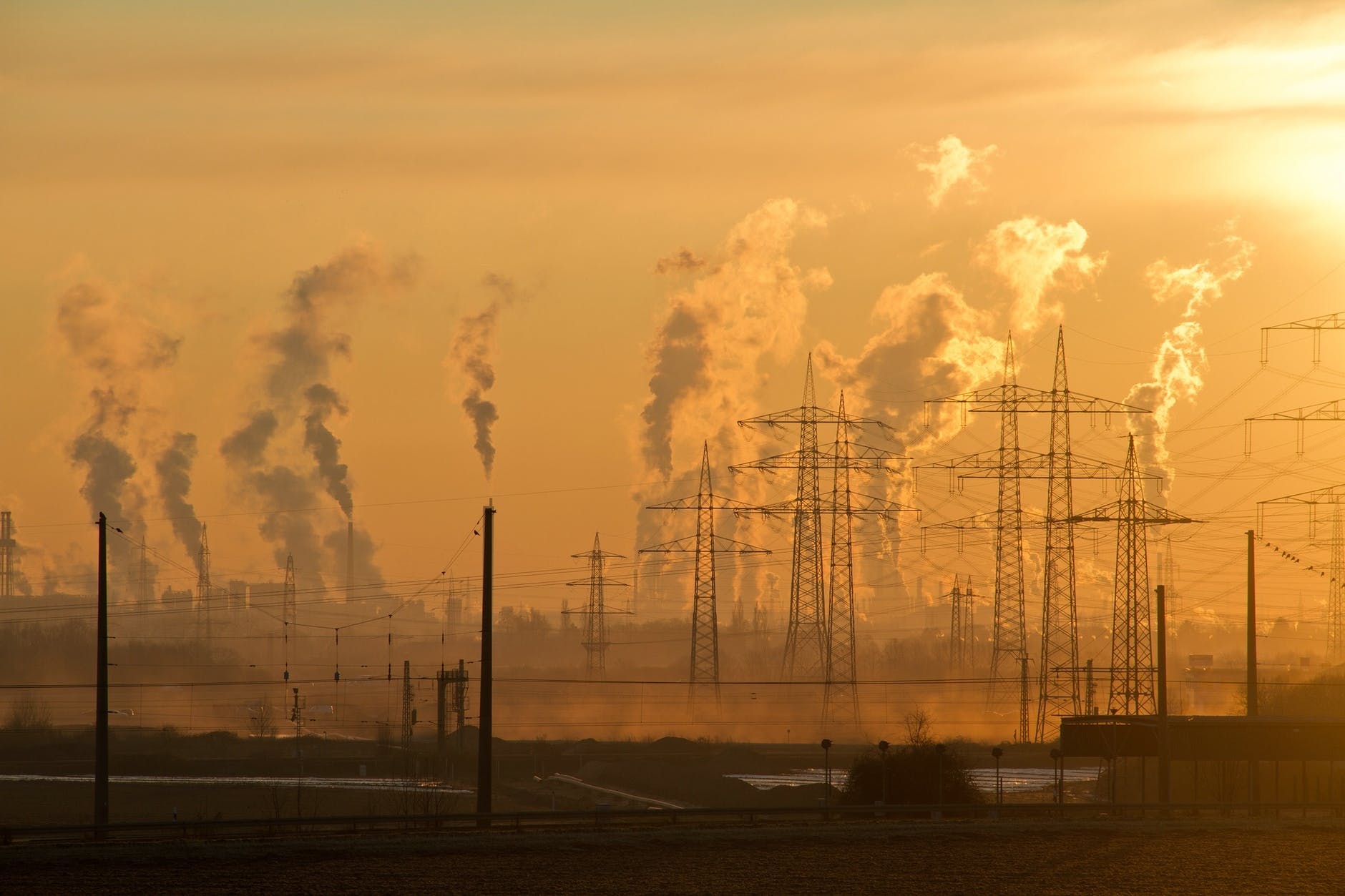 A sunrise over a cityscape highlighting air pollution and the need for renewable energy transition.