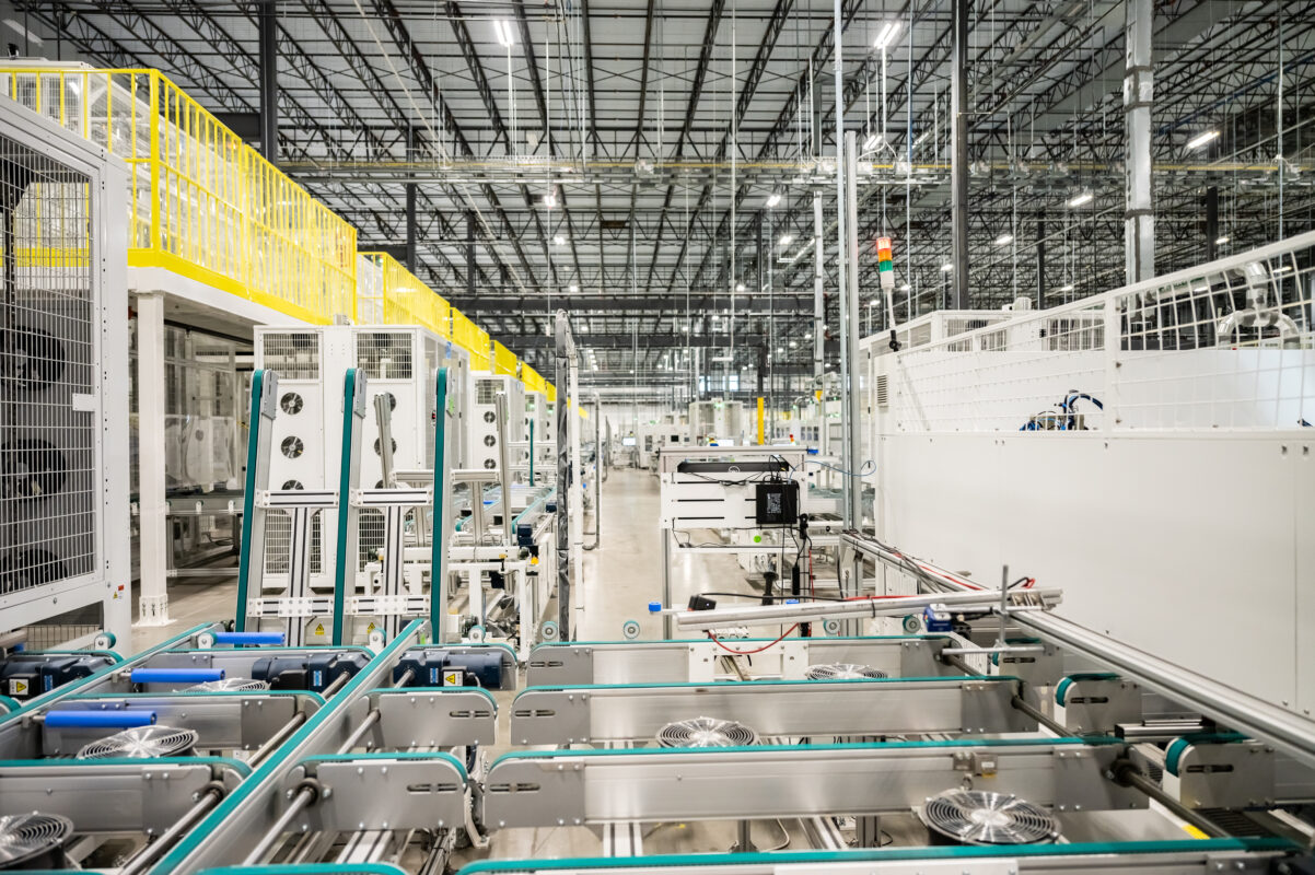 A modern solar panel manufacturing facility with rows of automated production machinery.