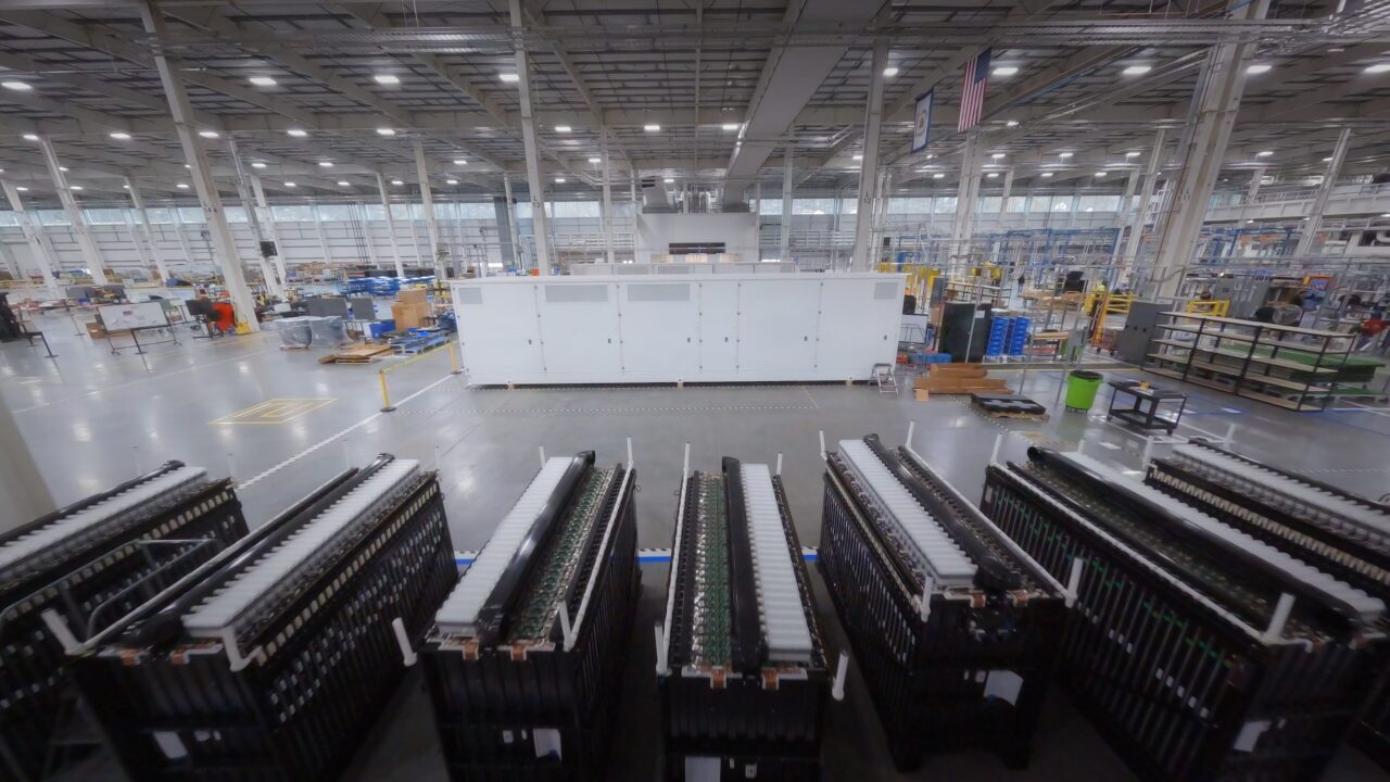 A row of industrial long-duration energy storage battery modules in a field installation.