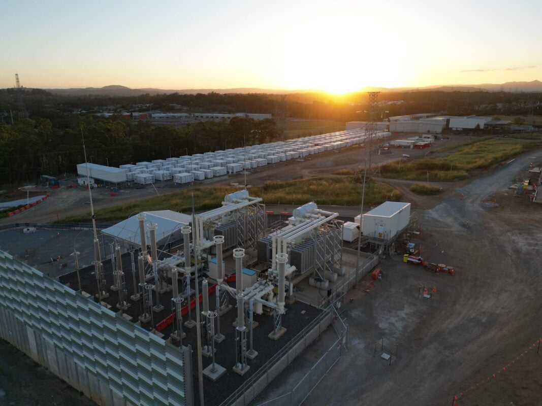 Aerial view of a massive utility-scale solar farm integrated with shipping-container-sized battery storage units.