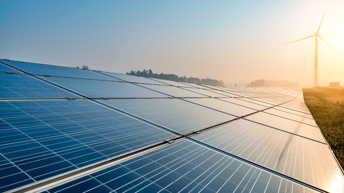 Aerial view of a massive solar array integrated with shipping-container-sized battery storage units.