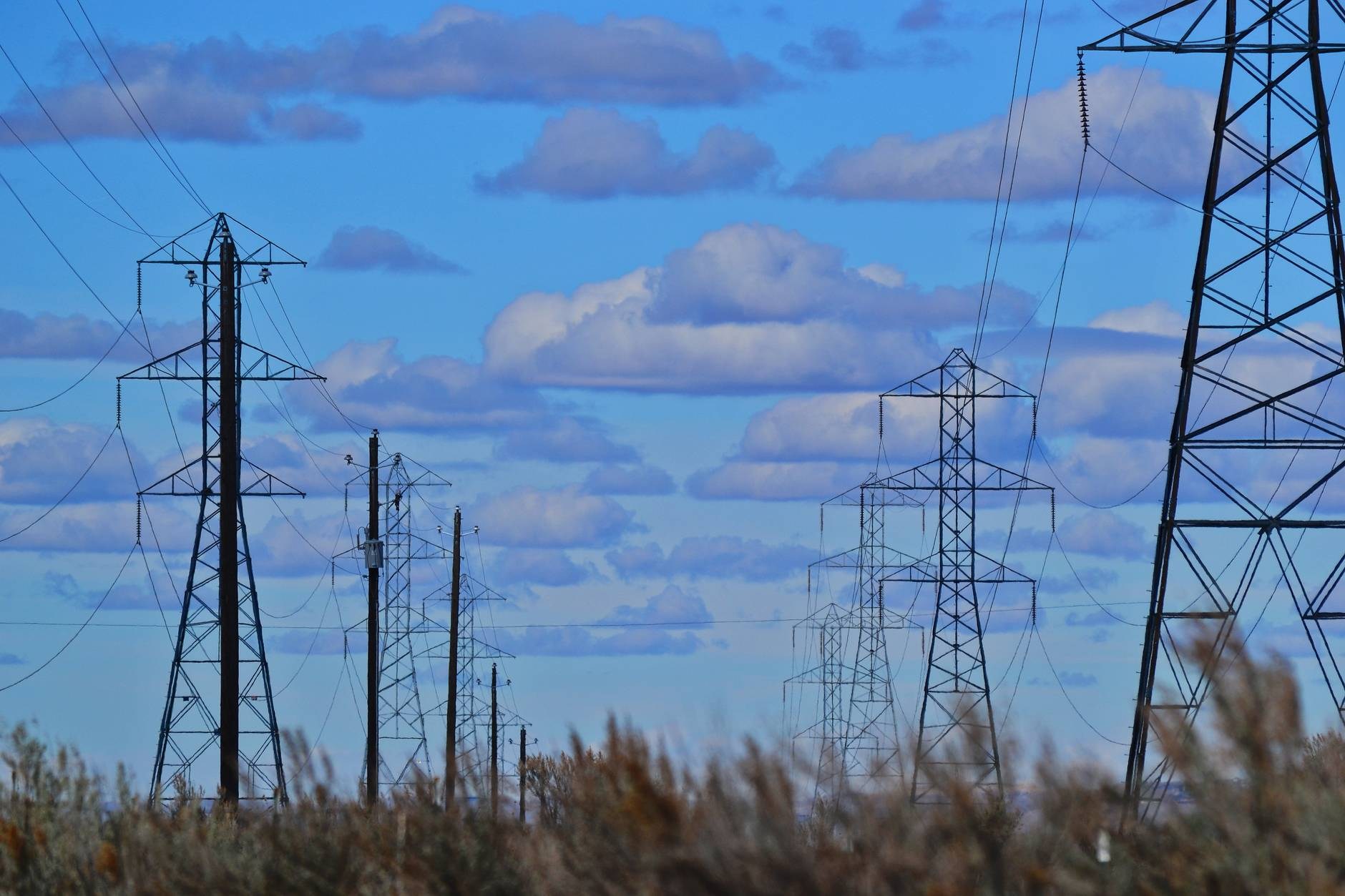 High voltage transmission lines against a sunset, representing green energy corridor infrastructure.