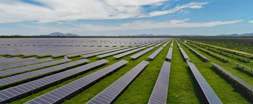 Aerial view of a massive utility-scale solar farm in the Australian outback under a clear blue sky.