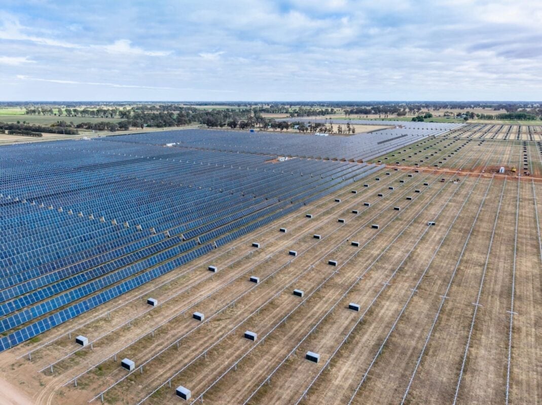 Aerial view of a massive solar array integrated into a dry, shrub-heavy landscape.