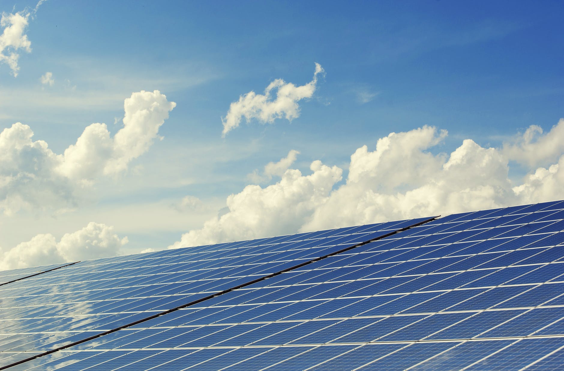 Large scale solar farm under construction with panels and blue sky.